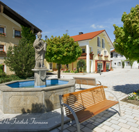 fileadmin/roha/images_galerie/orte_landschaft/Fridolfing/FRID-0005-D-roha-Fridolfing-Rupertus-Brunnen-Dorfplatz.png