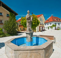 fileadmin/roha/images_galerie/orte_landschaft/Fridolfing/FRID-0007-D-roha-Fridolfing-Rupertus-Brunnen-Dorfplatz.png