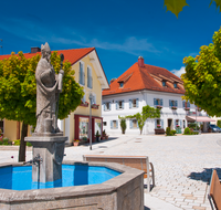 fileadmin/roha/images_galerie/orte_landschaft/Fridolfing/FRID-0008-D-roha-Fridolfing-Rupertus-Brunnen-Dorfplatz.png