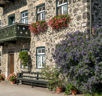 fileadmin/roha/Interessantes-in-Kurzform/ab-5-2023/LANDA-BLUMENSCHM-UFERING-0030-20-D-roha-Landart-Blumenschmuck-Bauernhaus-Enzianbaum.png