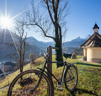 fileadmin/roha/Interessantes-in-Kurzform/BGD-KIRCHL-KAP-0043-D-roha-Berchtesgaden-Kirchleitn-Kapelle-Watzmann-Fahrrad-Sonne.png