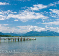 fileadmin/roha/images_galerie/orte_landschaft/Chiemsee/CHIE-STEG-CHIEM-0002-D-roha-Chiemsee-Chieming-Steg-Wasser-Berge-Kampenwand-Wolkenhimmel.png