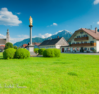 fileadmin/roha/images_galerie/orte_landschaft/Anger/Anger/AN-DORFPL-0001-02-D-roha-Anger-Dorfplatz-Mariensaeule-Kirche-Hochstaufen.png